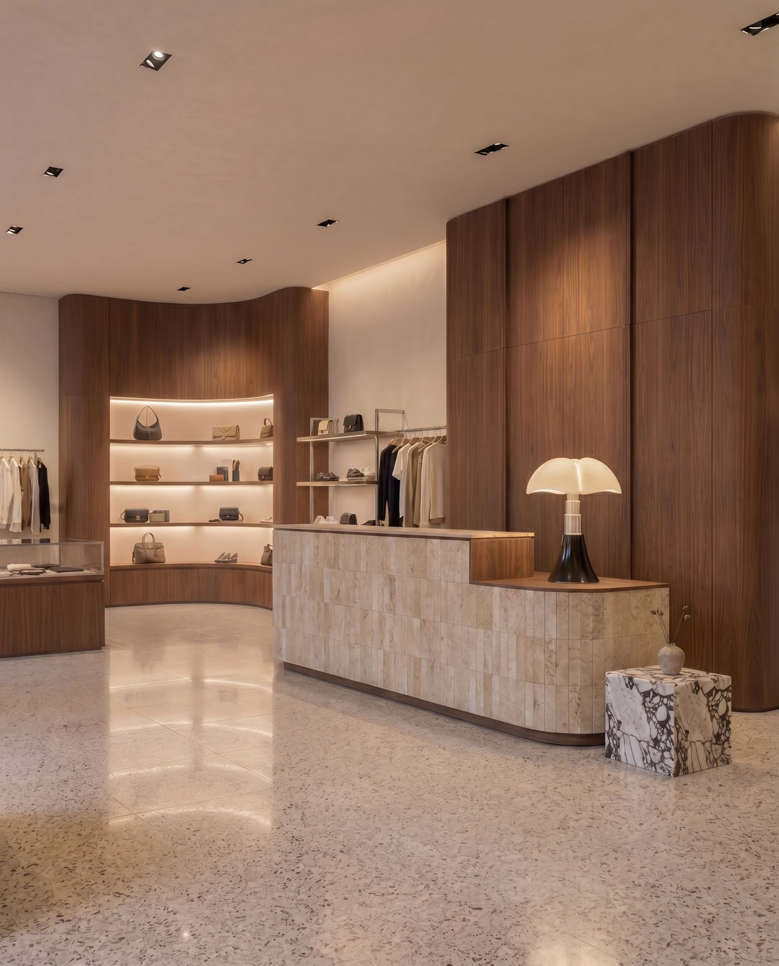 Boutique accessories display with curved walnut millwork and integrated lighting